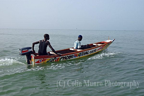 M'bour, Senegal. Two Senegalese fishermen head out to sea in a small pirogue (traditional wooden canoe).  Image MBI000909.