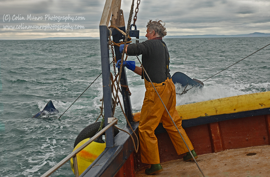 A fisherman lifts the steel wire warps, that tow the trawl net, in to blocks at the stern of the trawler. Colin Munro Photography