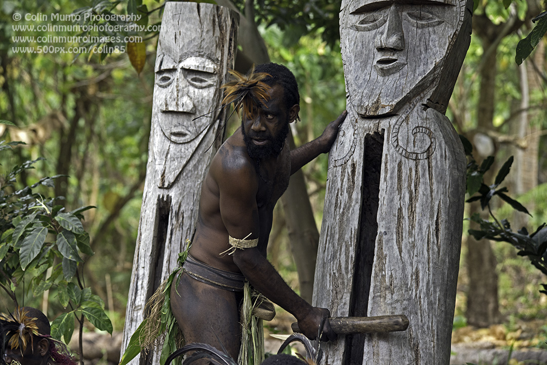 A drummer beats out a rhythm on hollow wooden statues, keeping the dancers in time. Malekula, Vanuatu. © Colin Munro Photography