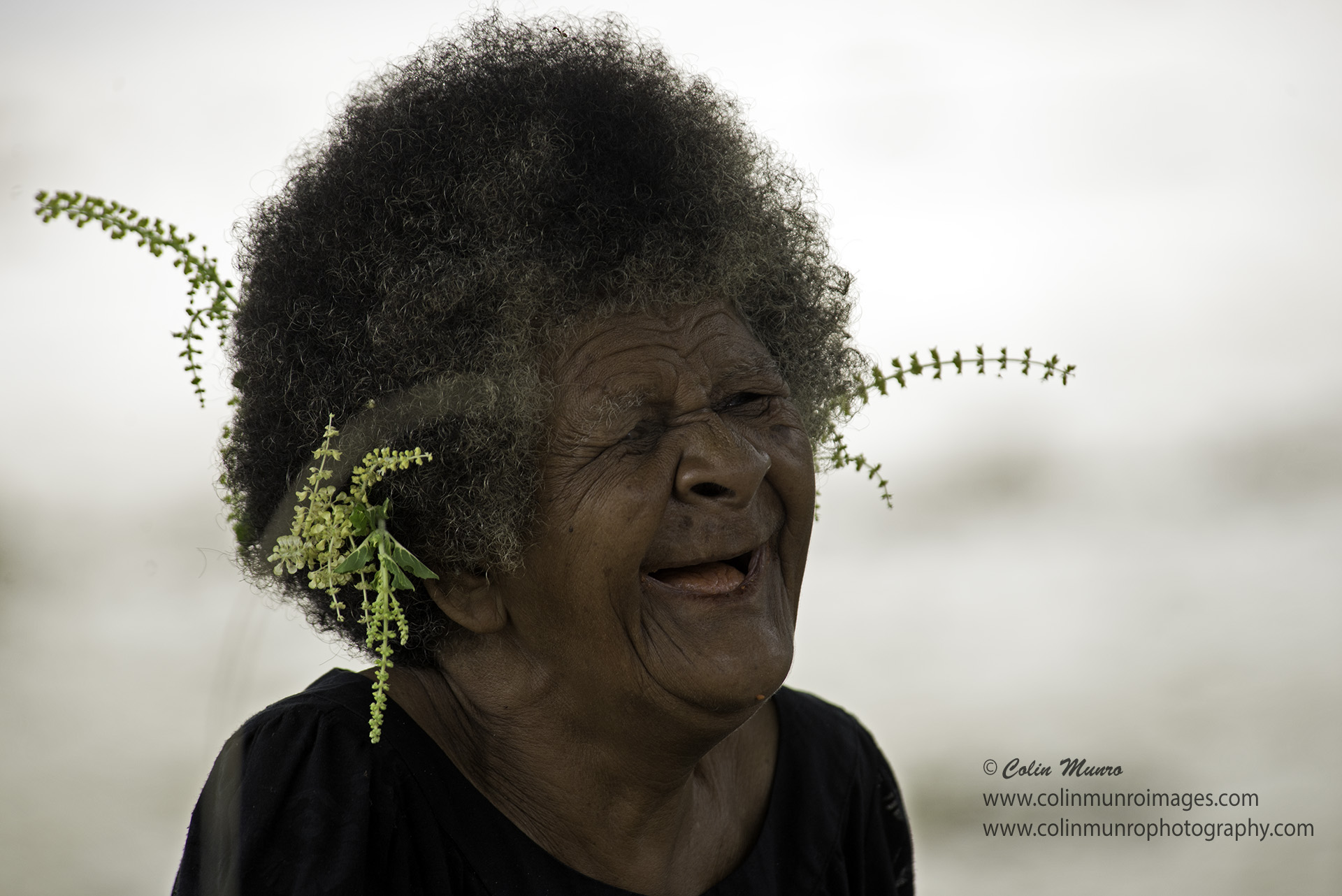 An old lady weaving pandanus leaves laughs as she works. Suau Island, Milne Bay Province, Papua New Guinea. Colin Munro Photography © Colin Munro