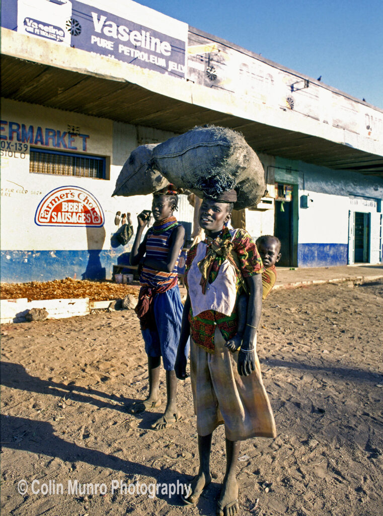 Isiolo, Kenya. 1980s. two girls carry sacks of charcoal to sell. www.colinmunrophotography.com
